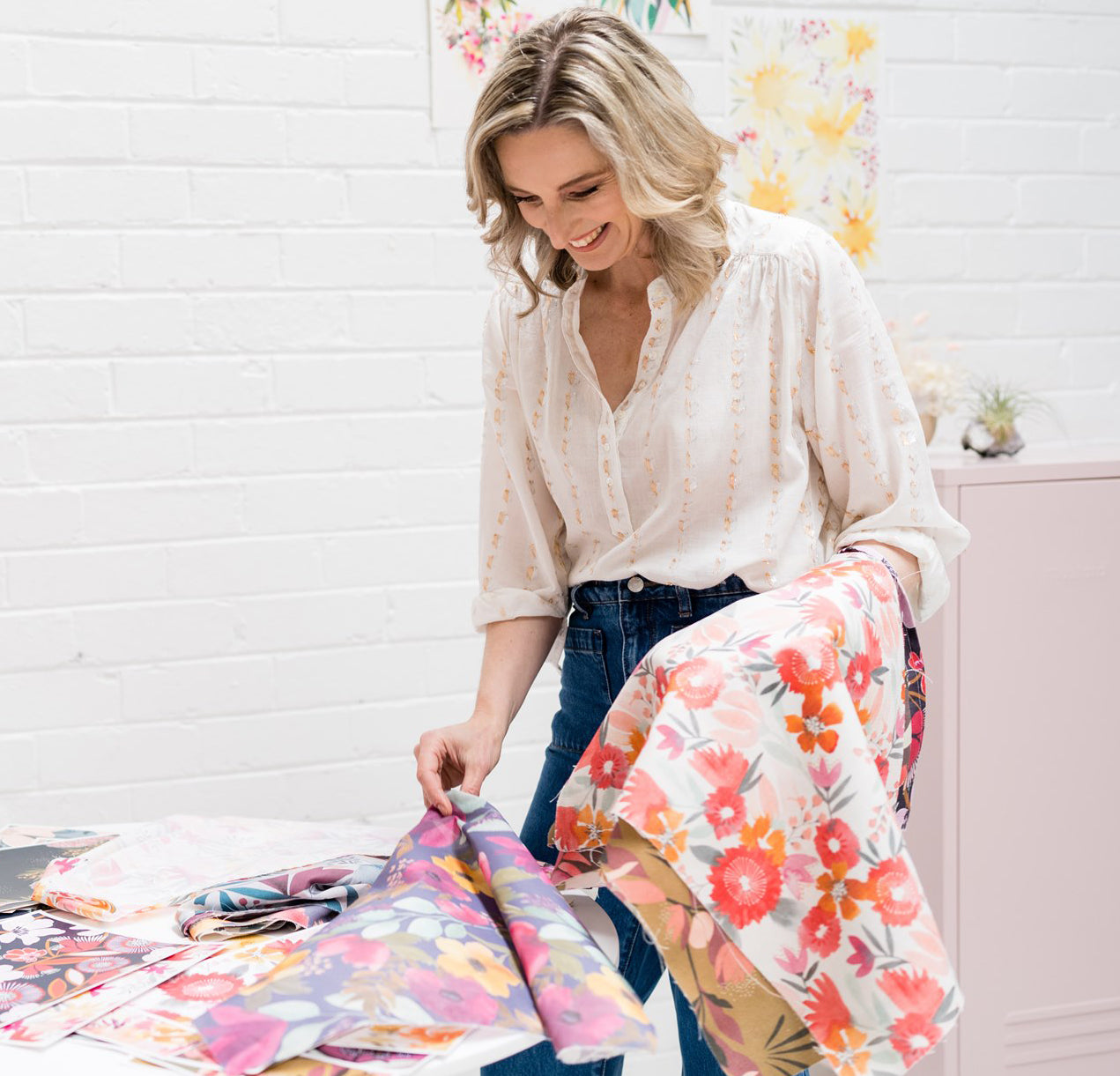 Rachelle Holowko standing at a table looking through beautifull floral fabrics